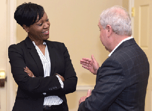 Yvette standing with crossed arms smiling and talking to a gentleman.